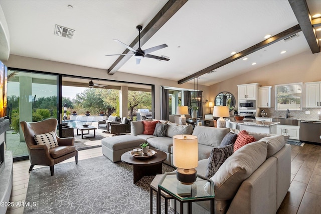 living room with ceiling fan, sink, and lofted ceiling with beams