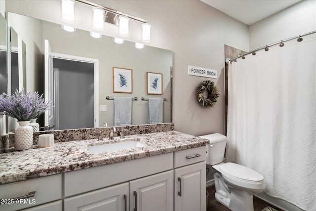 bathroom with toilet, a shower with shower curtain, and vanity