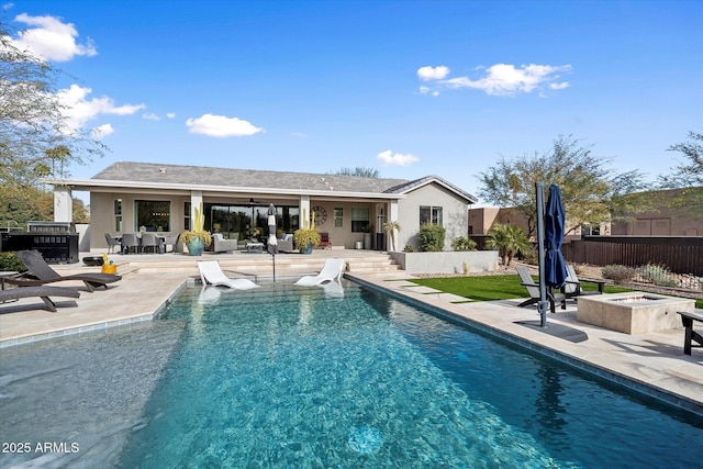 rear view of property with a fenced in pool, a patio area, and a fire pit