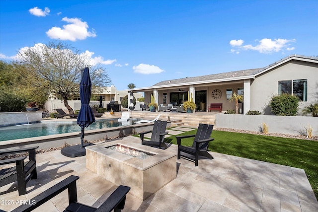 view of patio / terrace featuring a fenced in pool, a fire pit, and pool water feature