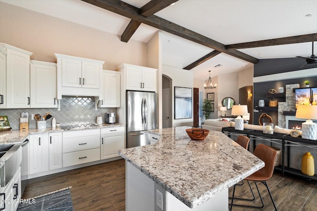 kitchen with a center island, white cabinetry, stainless steel fridge, a breakfast bar, and black electric cooktop