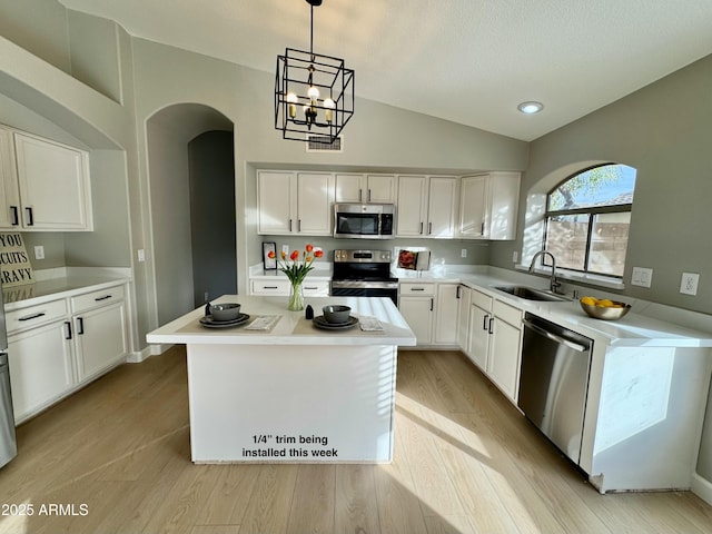 kitchen with white cabinetry, sink, pendant lighting, a kitchen island, and appliances with stainless steel finishes