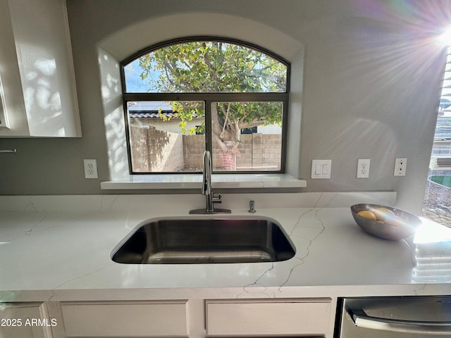 interior details with white cabinets, dishwasher, and sink