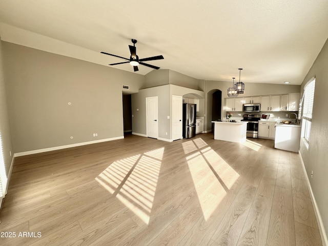 unfurnished living room featuring light hardwood / wood-style floors, vaulted ceiling, ceiling fan, and sink