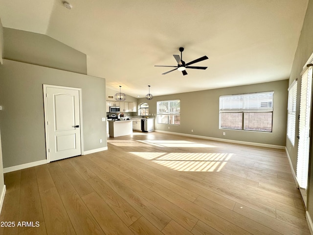 unfurnished living room featuring ceiling fan with notable chandelier, light hardwood / wood-style floors, and lofted ceiling