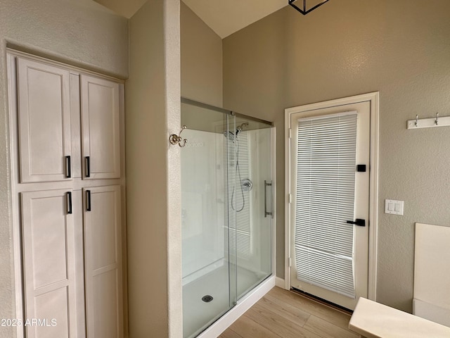 bathroom with hardwood / wood-style flooring and a shower with shower door