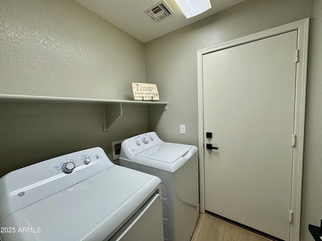 washroom featuring washing machine and dryer and light hardwood / wood-style floors