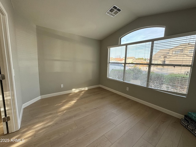 empty room with light wood-type flooring and lofted ceiling