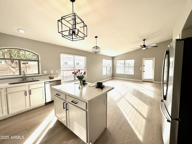 kitchen featuring sink, stainless steel appliances, a kitchen island, pendant lighting, and white cabinets