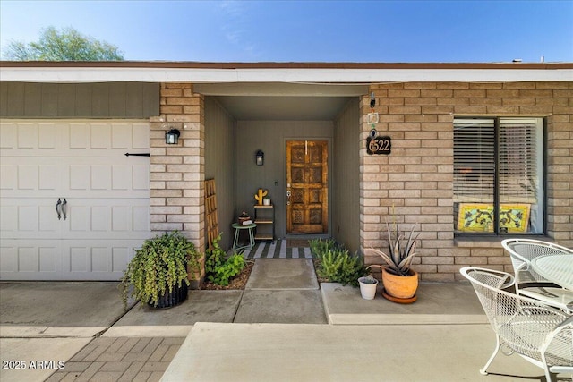 doorway to property featuring a garage and brick siding