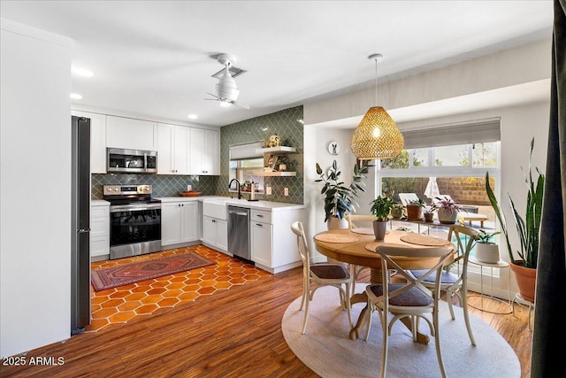 kitchen featuring stainless steel appliances, a sink, white cabinetry, light countertops, and tasteful backsplash