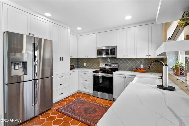 kitchen featuring light stone countertops, tasteful backsplash, white cabinetry, and stainless steel appliances