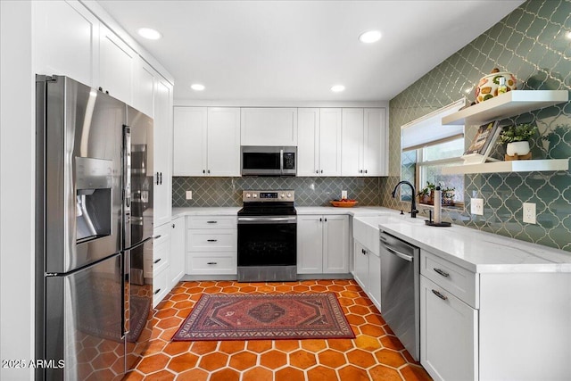 kitchen featuring wallpapered walls, white cabinets, light stone countertops, stainless steel appliances, and open shelves