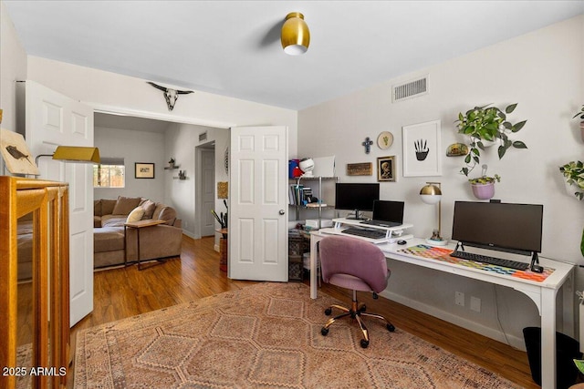 office with baseboards, visible vents, and wood finished floors