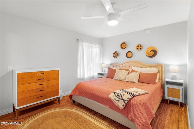 bedroom featuring a ceiling fan, baseboards, and wood finished floors