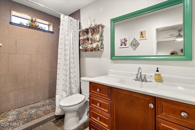 bathroom with a ceiling fan, tiled shower, vanity, and toilet