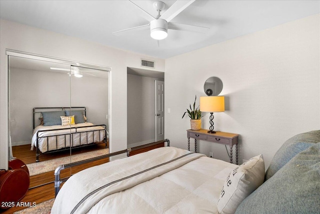 bedroom featuring baseboards, visible vents, ceiling fan, wood finished floors, and a closet