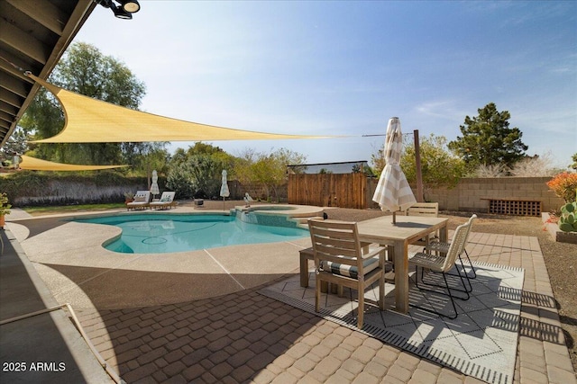 view of pool featuring outdoor dining space, a pool with connected hot tub, a patio area, and a fenced backyard