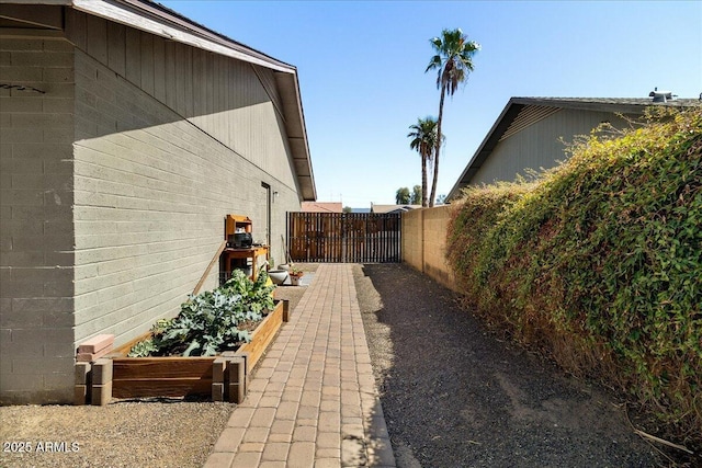 view of property exterior with concrete block siding, a vegetable garden, and fence