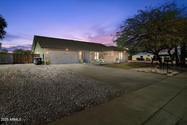 ranch-style home featuring concrete driveway, brick siding, an attached garage, and fence