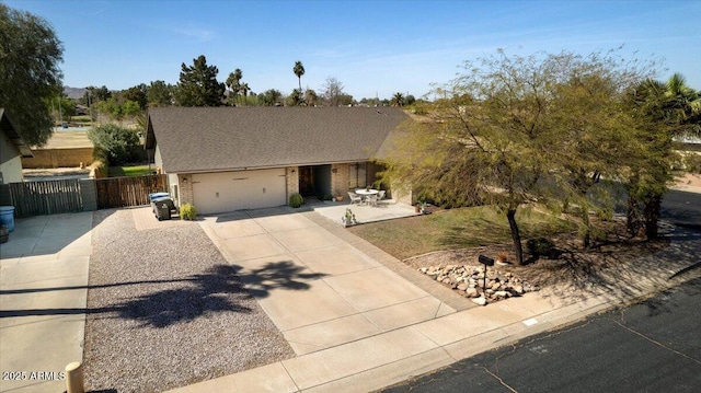 view of front of property featuring a garage, driveway, brick siding, and fence