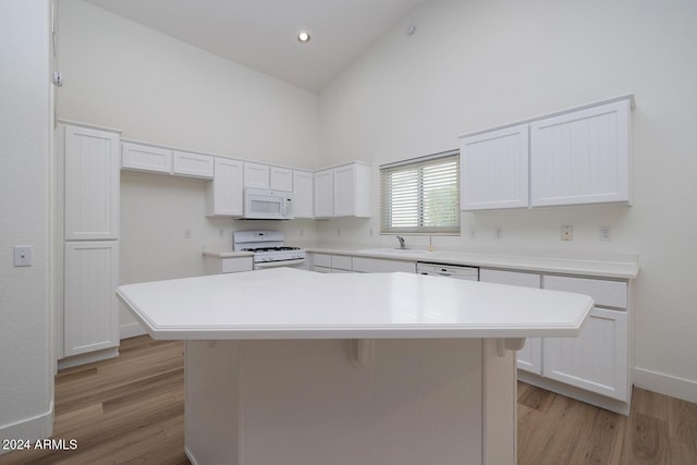 3956 N 151st Dr, Goodyear, AZ 85395 - kitchen with white appliances, high vaulted ceiling, light wood finished floors, white cabinets, and a kitchen island