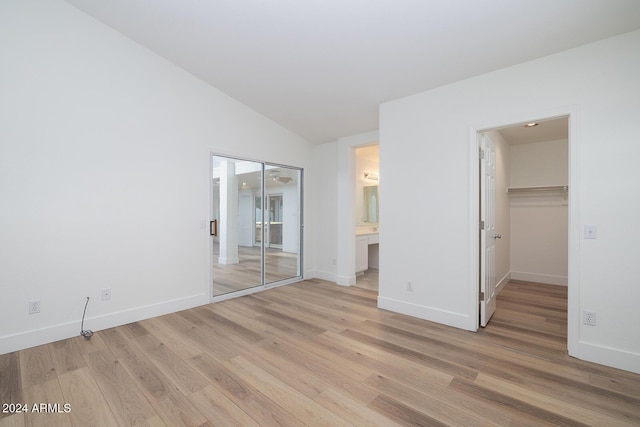 3956 N 151st Dr, Goodyear, AZ 85395 - unfurnished bedroom featuring light wood-style floors, lofted ceiling, a closet, a walk in closet, and ensuite bathroom