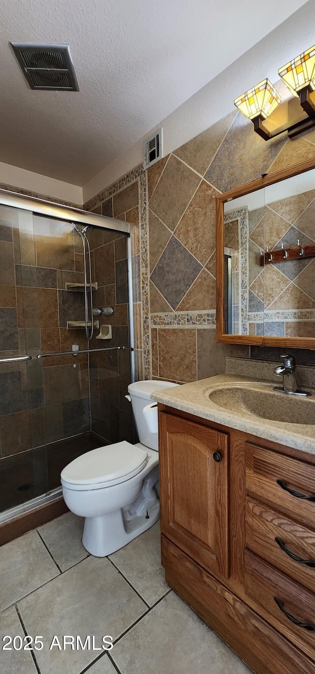 full bath featuring a textured ceiling, tile patterned flooring, visible vents, tile walls, and a stall shower