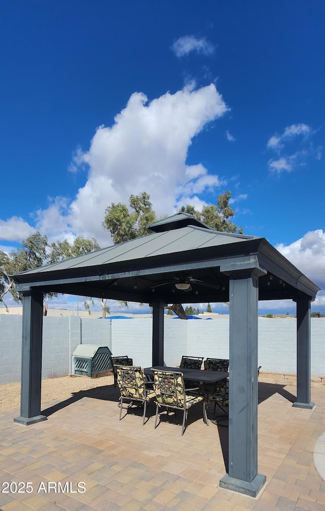 view of patio with outdoor dining space, fence, and a gazebo