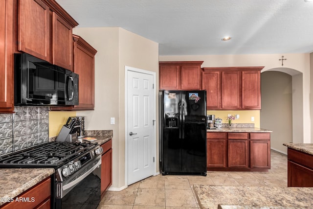 kitchen with arched walkways, black appliances, tasteful backsplash, and baseboards