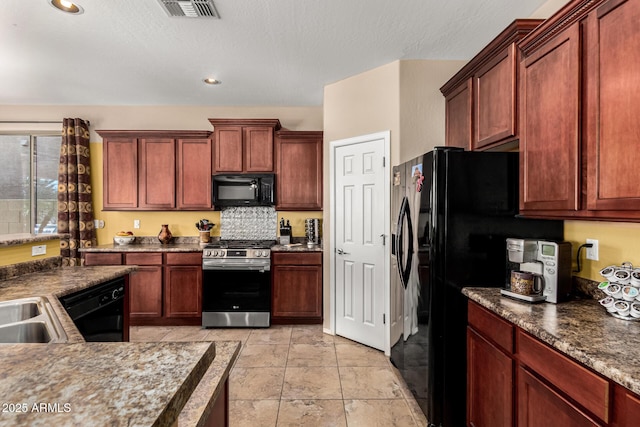 kitchen with dark countertops, visible vents, a sink, and black appliances