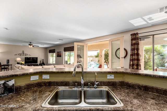 kitchen featuring open floor plan, dark countertops, a sink, and visible vents