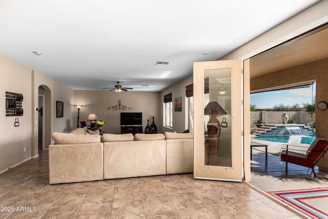 living area with arched walkways, visible vents, and ceiling fan