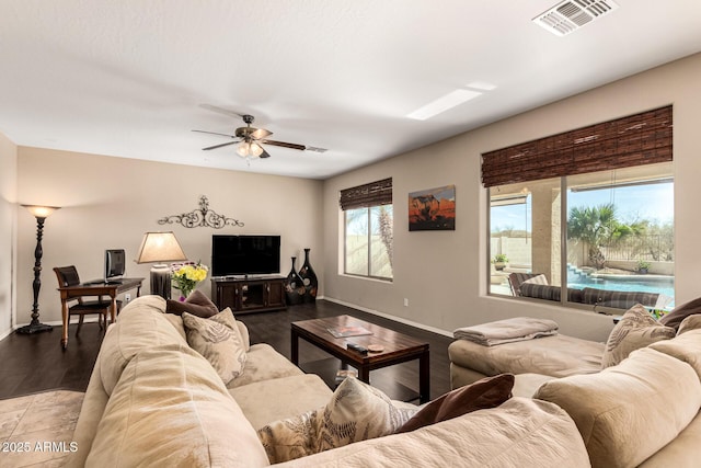 living area featuring a ceiling fan, visible vents, baseboards, and wood finished floors