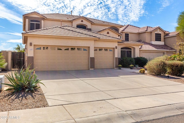 mediterranean / spanish home featuring a garage, concrete driveway, a tiled roof, and stucco siding