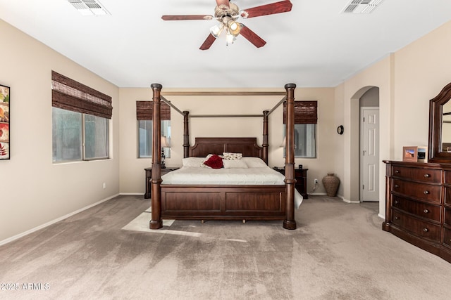 bedroom featuring arched walkways, visible vents, light carpet, and baseboards