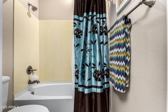 full bath with a textured wall, shower / tub combo, and toilet