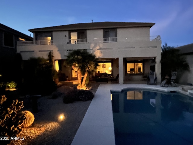 rear view of house featuring an outdoor pool, a patio, and a balcony