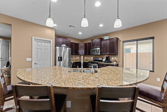 kitchen with pendant lighting, dark brown cabinetry, stainless steel appliances, and a breakfast bar area