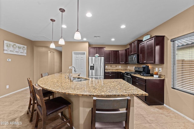 kitchen with pendant lighting, sink, a kitchen breakfast bar, stainless steel appliances, and a center island with sink