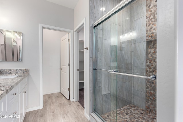 bathroom featuring hardwood / wood-style floors, a shower with shower door, and vanity