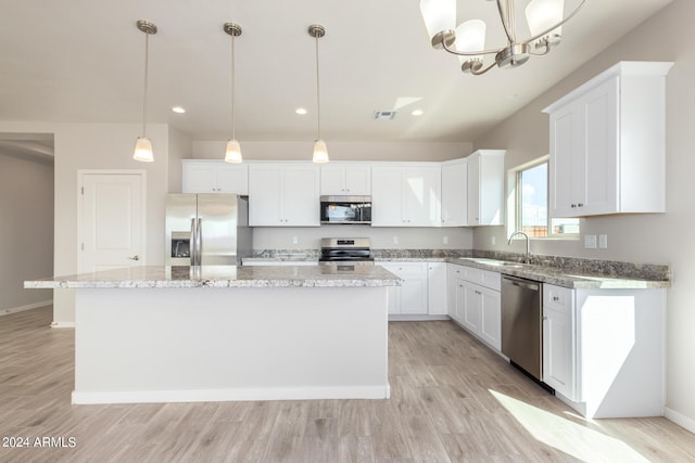 kitchen featuring stainless steel appliances, white cabinetry, a center island, and hanging light fixtures