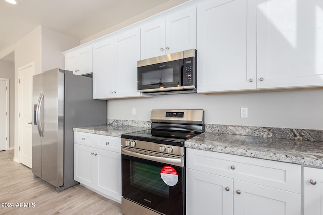 kitchen featuring appliances with stainless steel finishes, light hardwood / wood-style floors, light stone countertops, and white cabinets