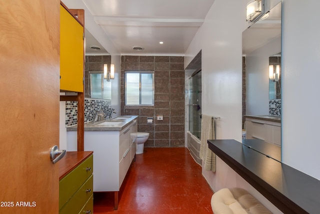 full bathroom featuring toilet, concrete flooring, combined bath / shower with glass door, tile walls, and vanity