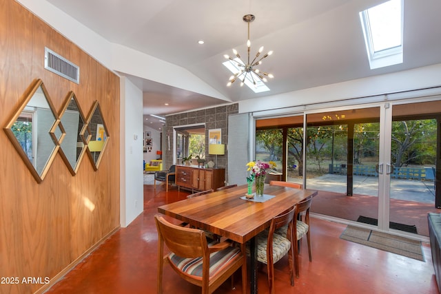 dining space with lofted ceiling with skylight and a notable chandelier