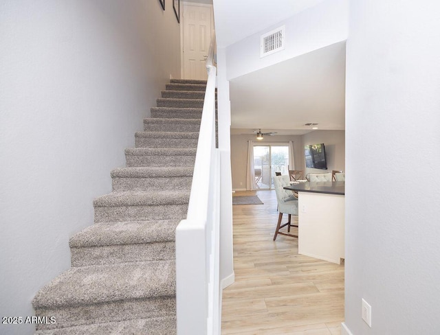 stairs with wood-type flooring and ceiling fan