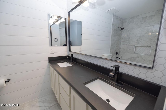 bathroom with tiled shower, vanity, toilet, and wood walls