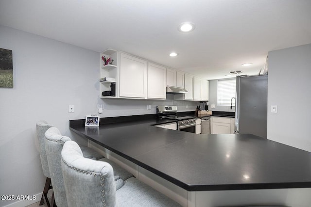 kitchen with appliances with stainless steel finishes, white cabinets, and kitchen peninsula