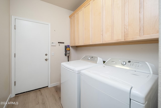 clothes washing area featuring light hardwood / wood-style flooring, cabinets, and washer and dryer