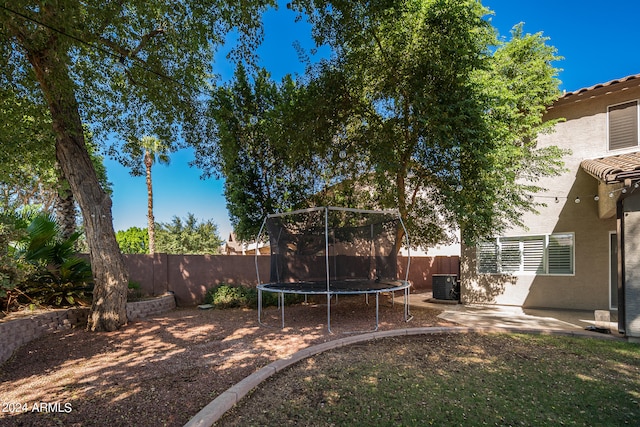 view of yard with a trampoline, central AC unit, and a patio area